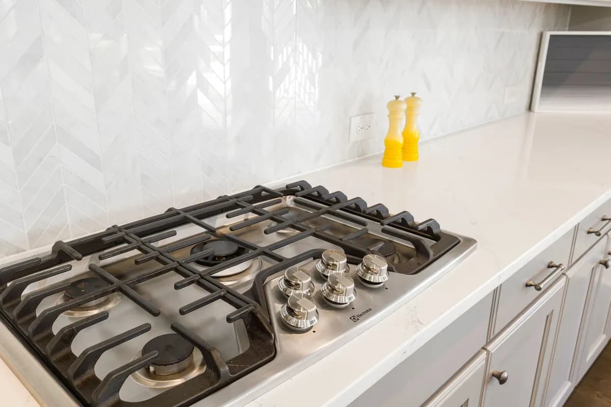 Gas cooktop set into a white kitchen countertop