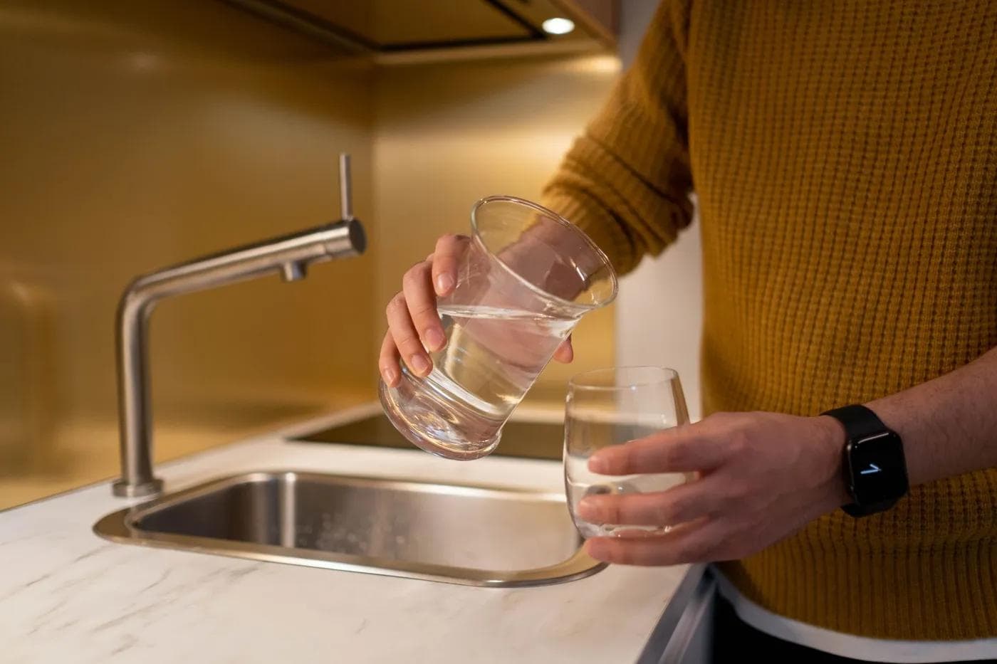 Water being poured from a pitcher into a glass in a kitchen